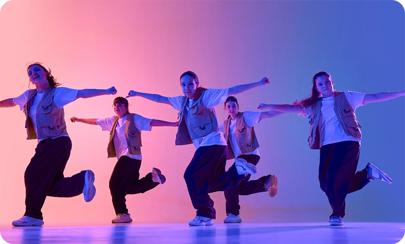 Hip hop dance class students performing under colourful stage lighting